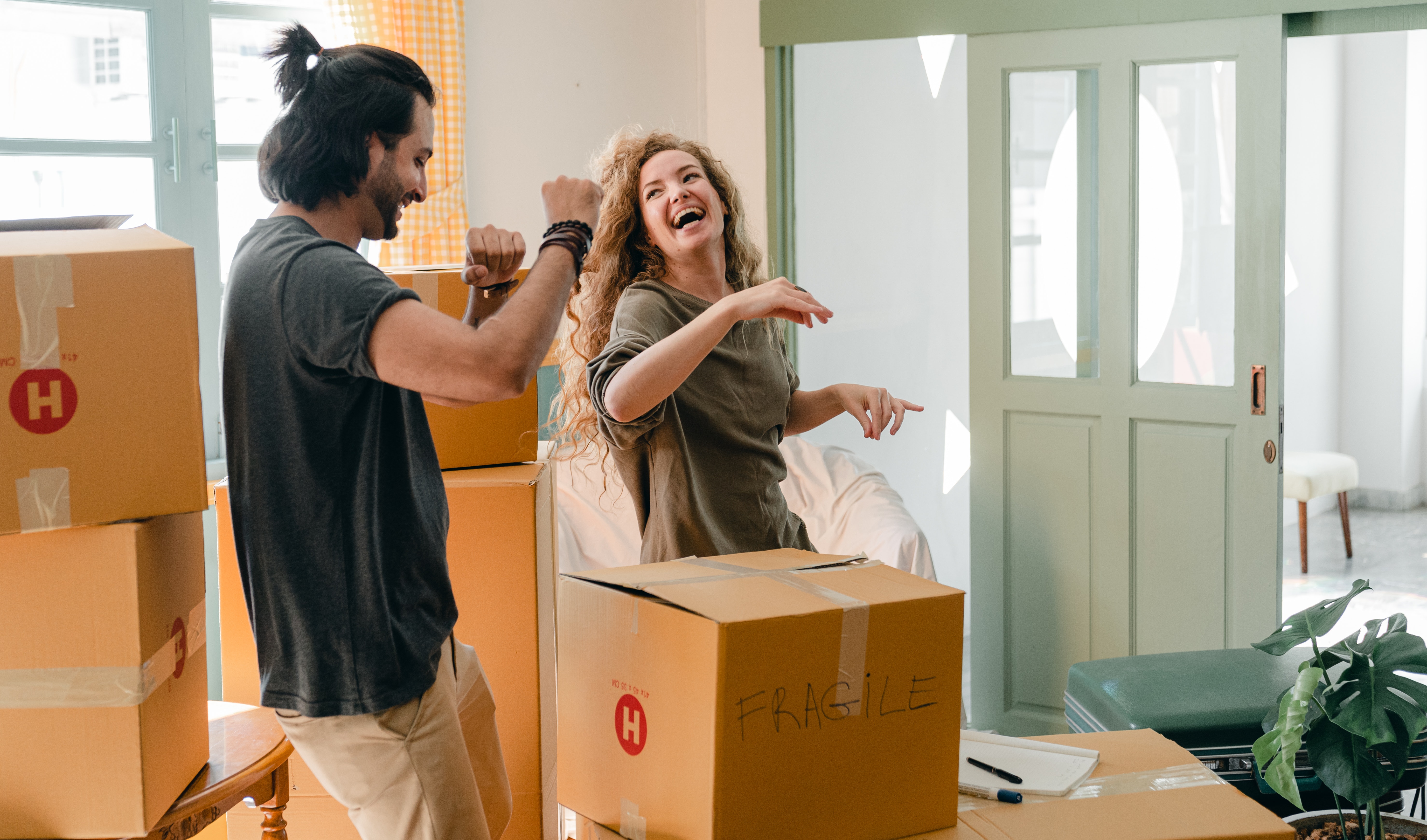 stock photo of couple unpacking sets of moving boxes in new home.